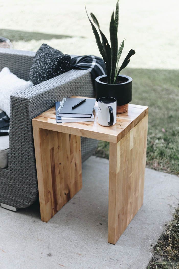 a table with a book, coffee cup and potted plant on it next to a couch