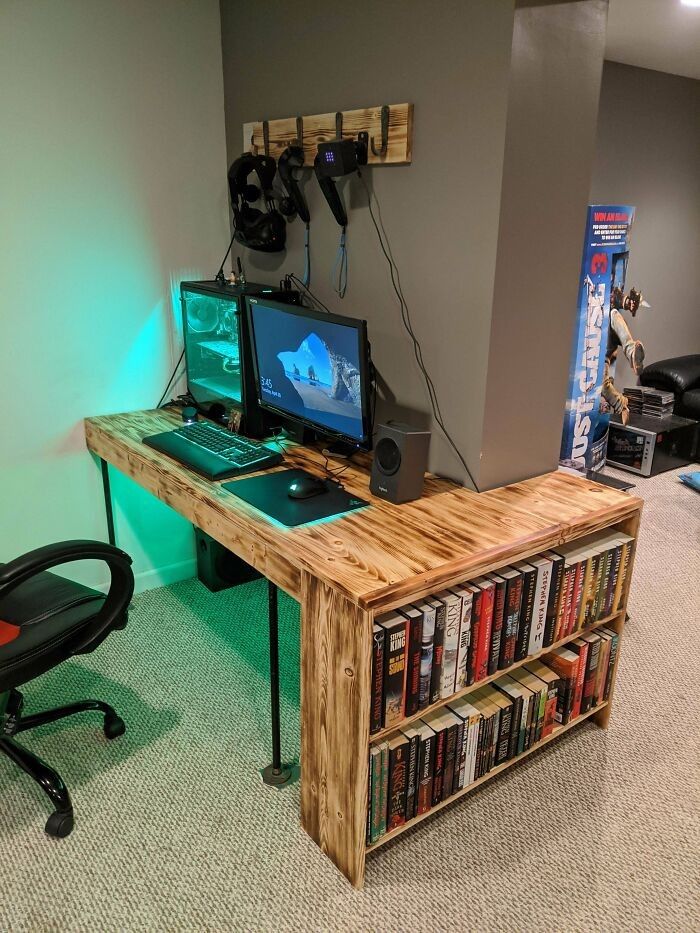 a computer desk with two computers on top of it next to a book shelf filled with books