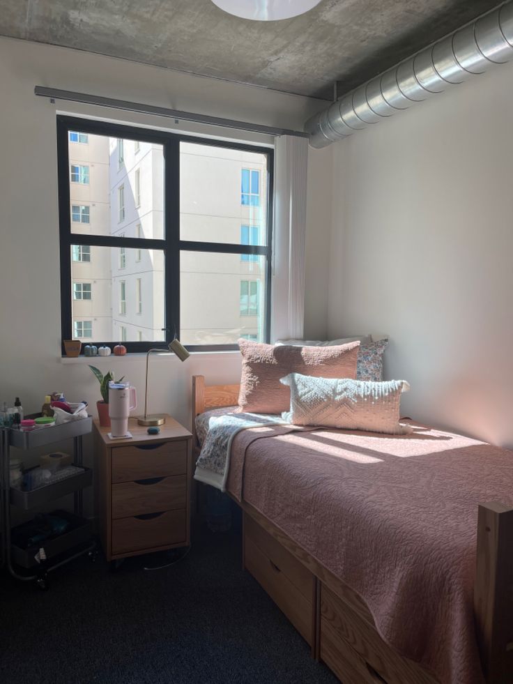 a bed sitting under a window next to a wooden dresser