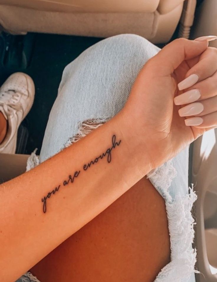 a woman's arm with the words you are enough tattooed on her left arm