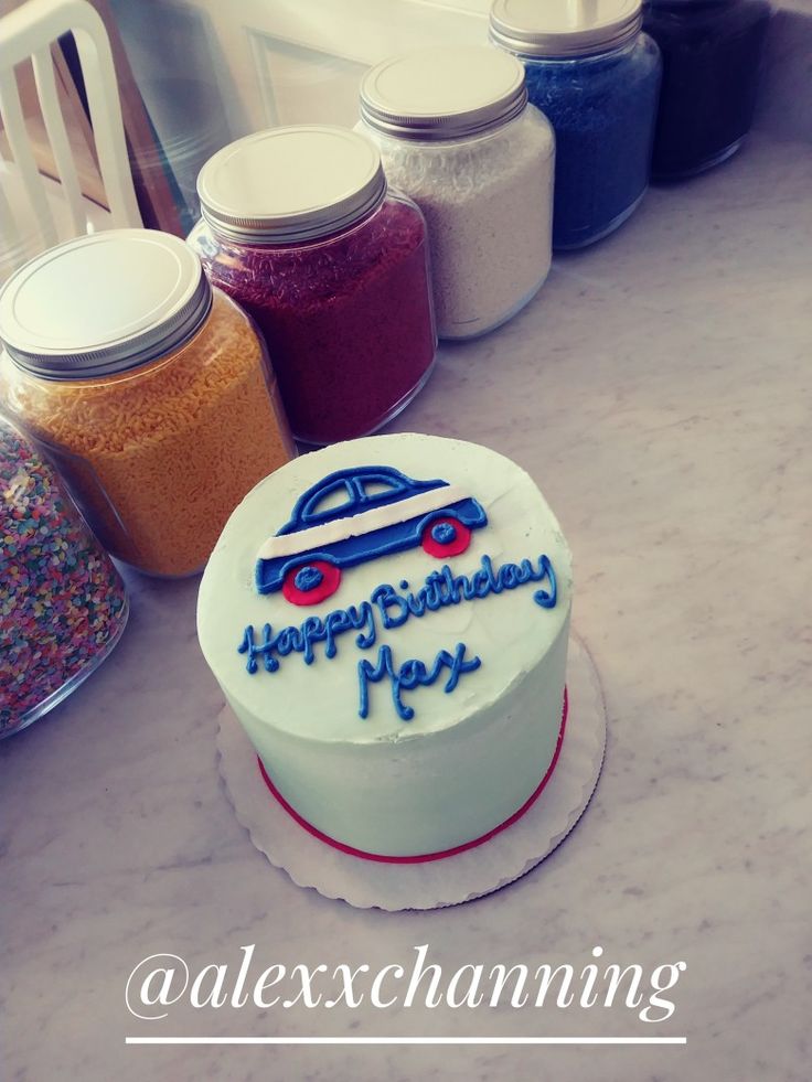 a birthday cake sitting on top of a counter next to jars filled with sprinkles