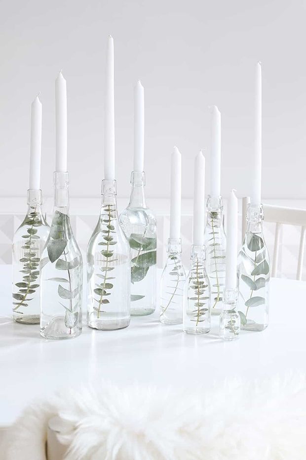 there are many bottles with plants in them on the table and one is filled with candles