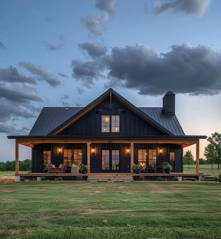 a large black house sitting on top of a lush green field