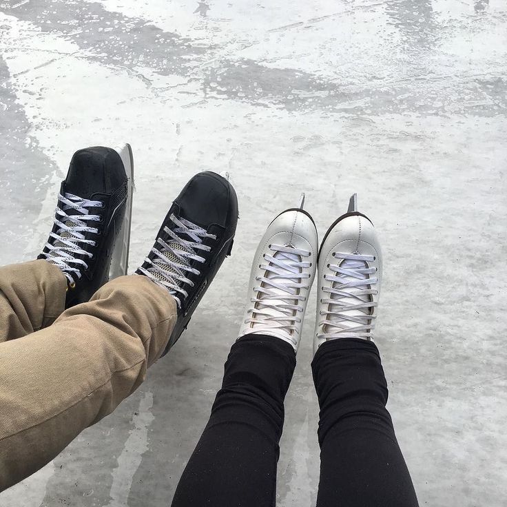 two people wearing black and white sneakers sitting on ice