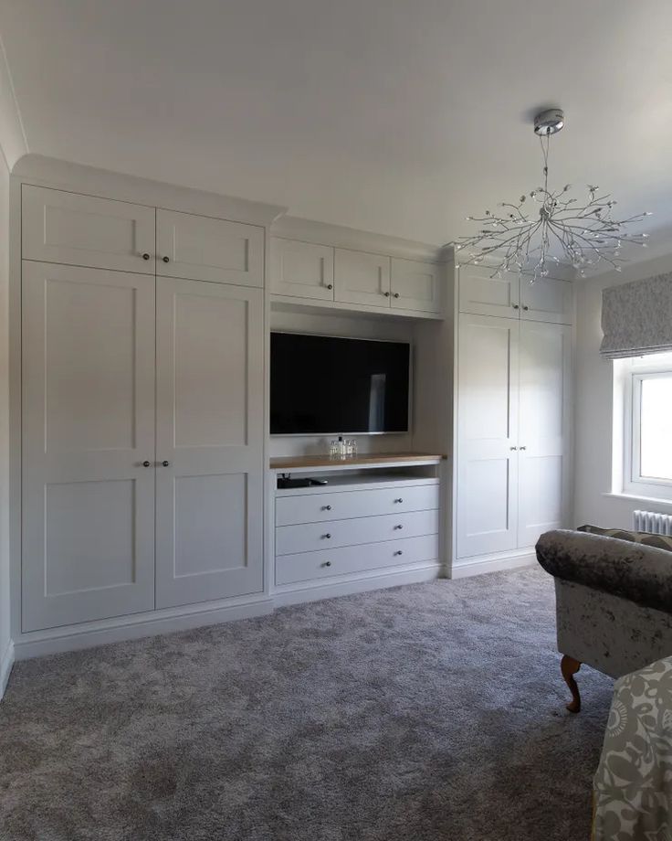 an empty room with white cabinets and a television