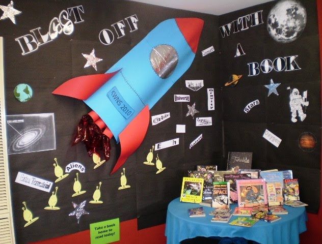 a bulletin board with a rocket ship on it and other items for reading in front of it