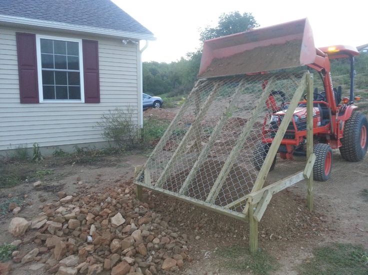 a tractor is parked in front of a house with a chicken cage attached to it