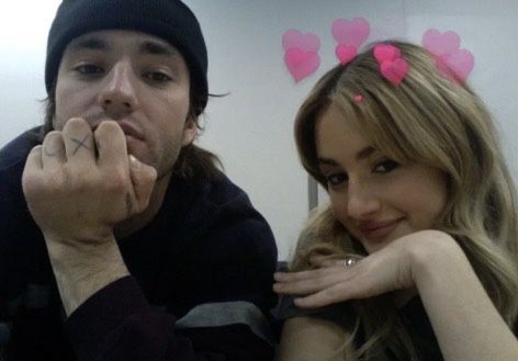 a man and woman posing for the camera with hearts on their foreheads behind them