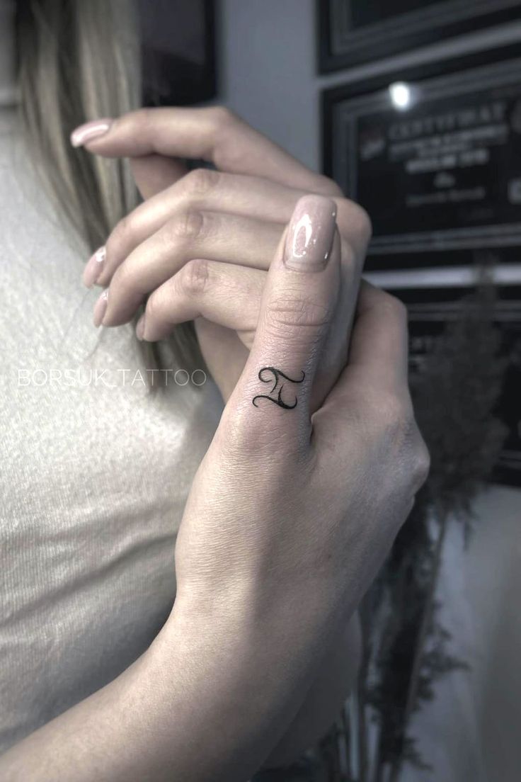 a woman's hand with a small tattoo on her left wrist and the word love written