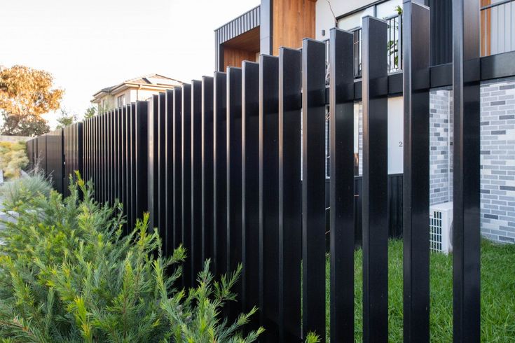 a black fence is next to some bushes