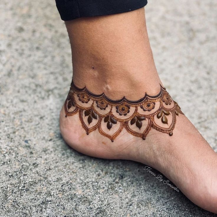 a woman's foot with a henna tattoo on the top of her leg