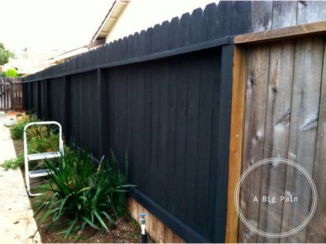 a white lawn chair sitting next to a black fence and green plants in front of it