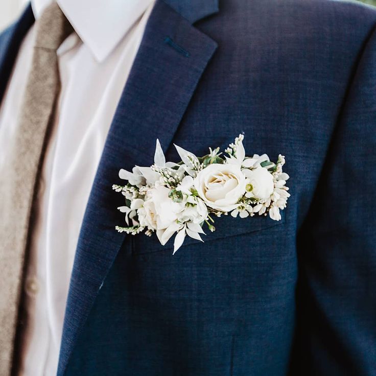 a man wearing a blue suit with white flowers on it's lapel pin