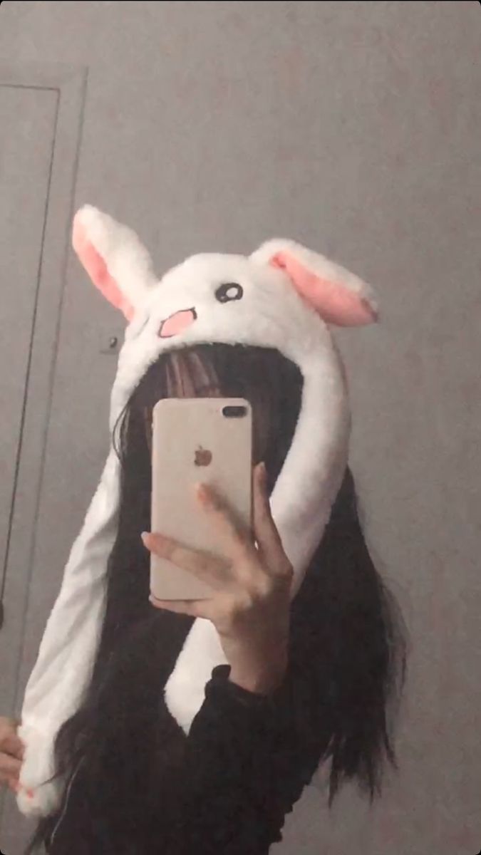 a woman taking a selfie in front of a mirror wearing a bunny ears hat