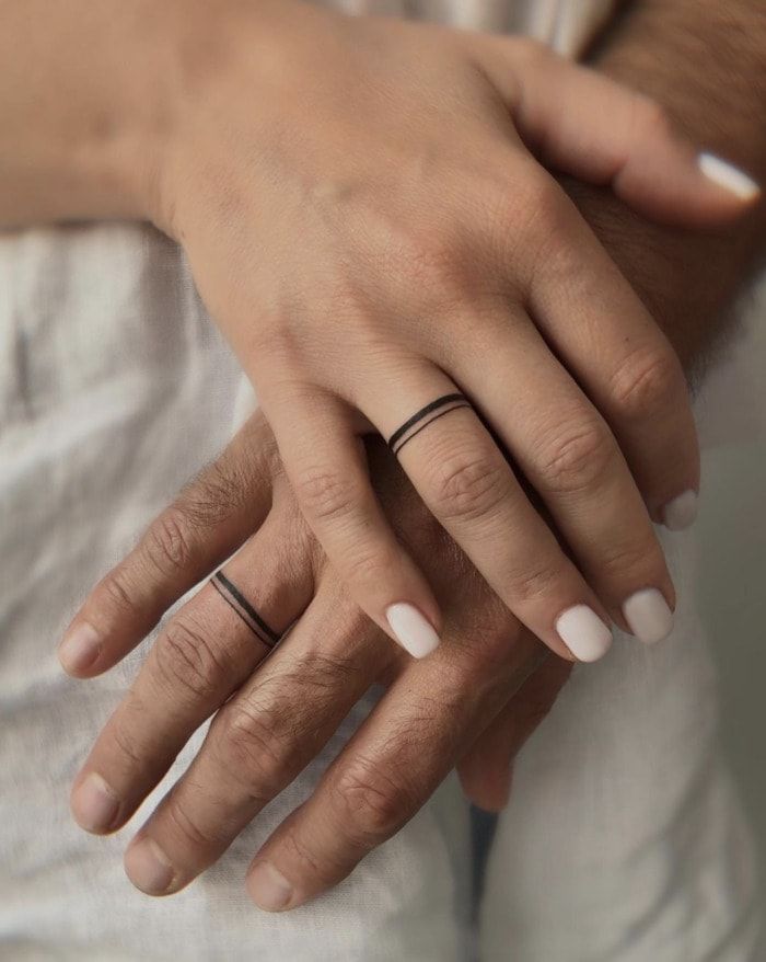 two people with wedding rings on their hands, one holding the other's hand