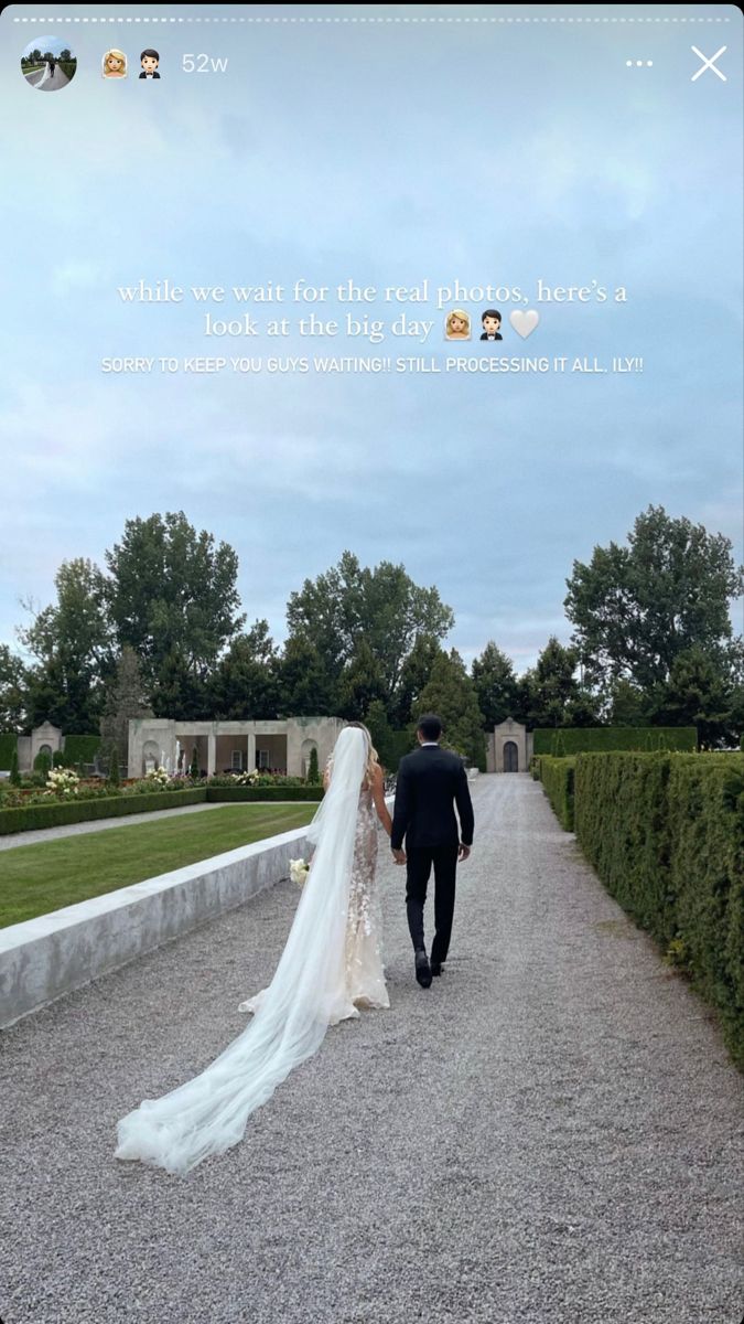 a bride and groom walking down a gravel path together in front of an elegant garden