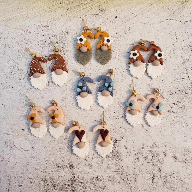 six pairs of earrings with animal heads on them sitting in the sand next to each other