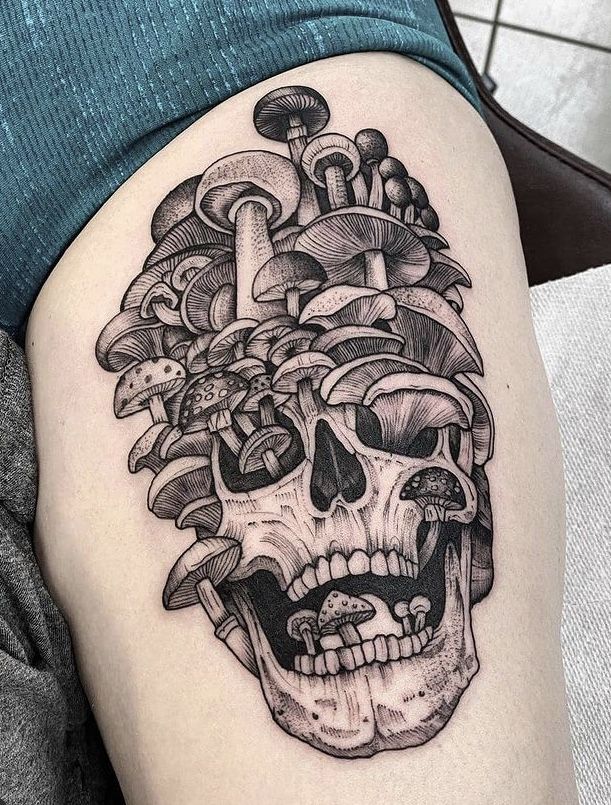 a woman's thigh with a skull and mushrooms on it