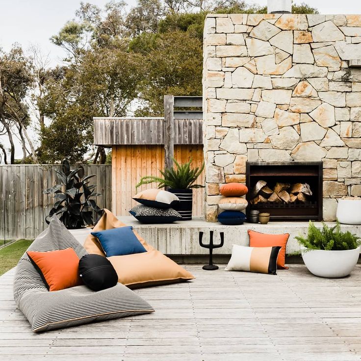 an outdoor fireplace and seating area with various pillows