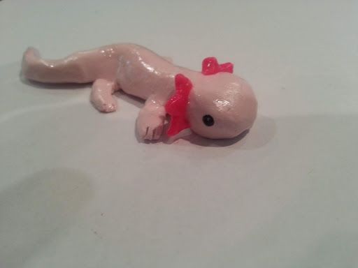 a toy gecko laying on top of a white table next to a red object