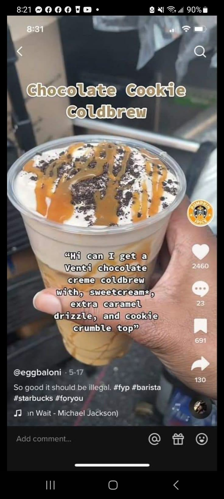 someone holding up a cup of ice cream with caramel and chocolate toppings on top