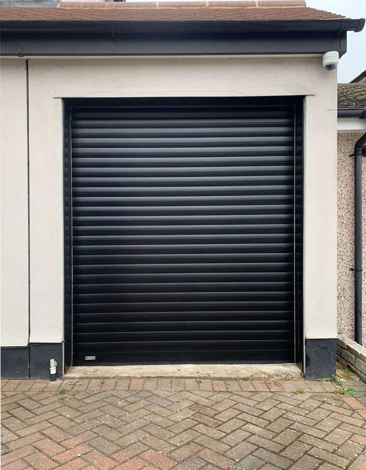 a garage door is closed on the side of a brick driveway in front of a house