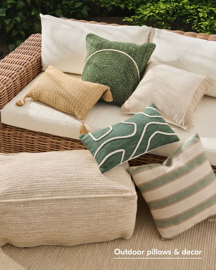 several pillows are arranged on a wicker couch