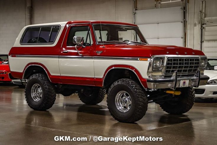 an old red and white truck parked in a garage