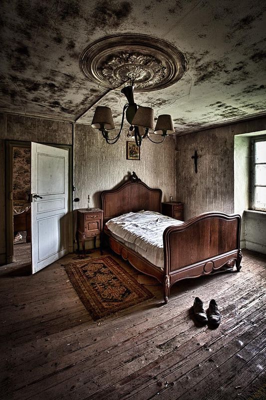 an old bedroom with a bed, chandelier and rug on the wooden floor