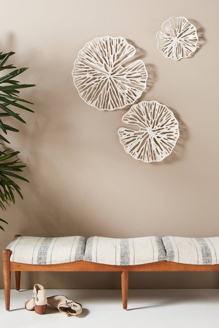 three circular wall hangings above a bench with shoes on the floor next to it