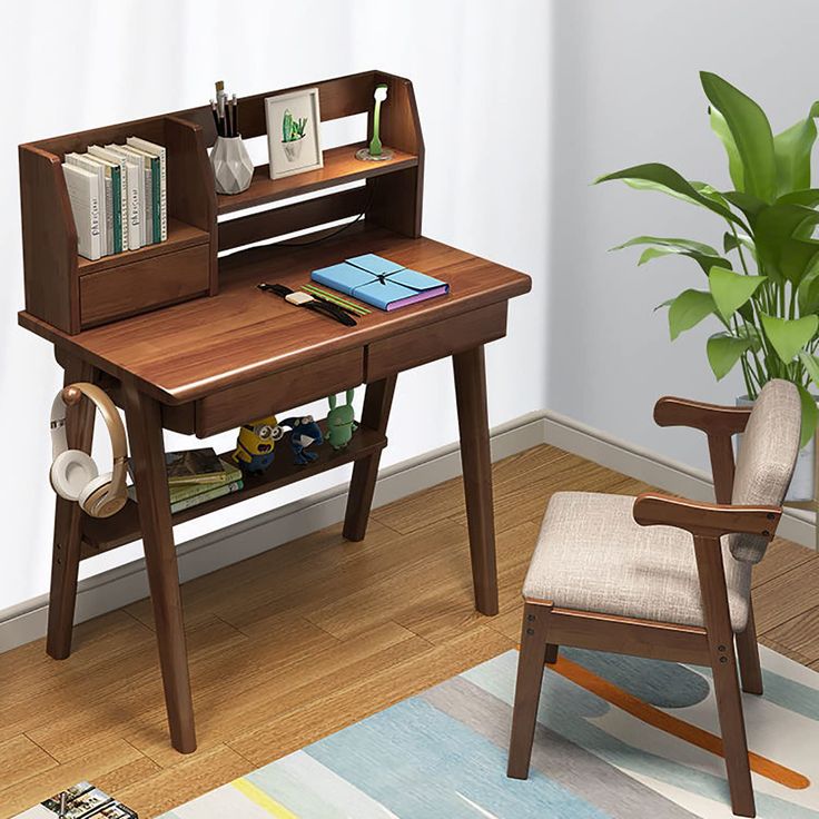 a wooden desk with a chair next to it and a potted plant in the corner