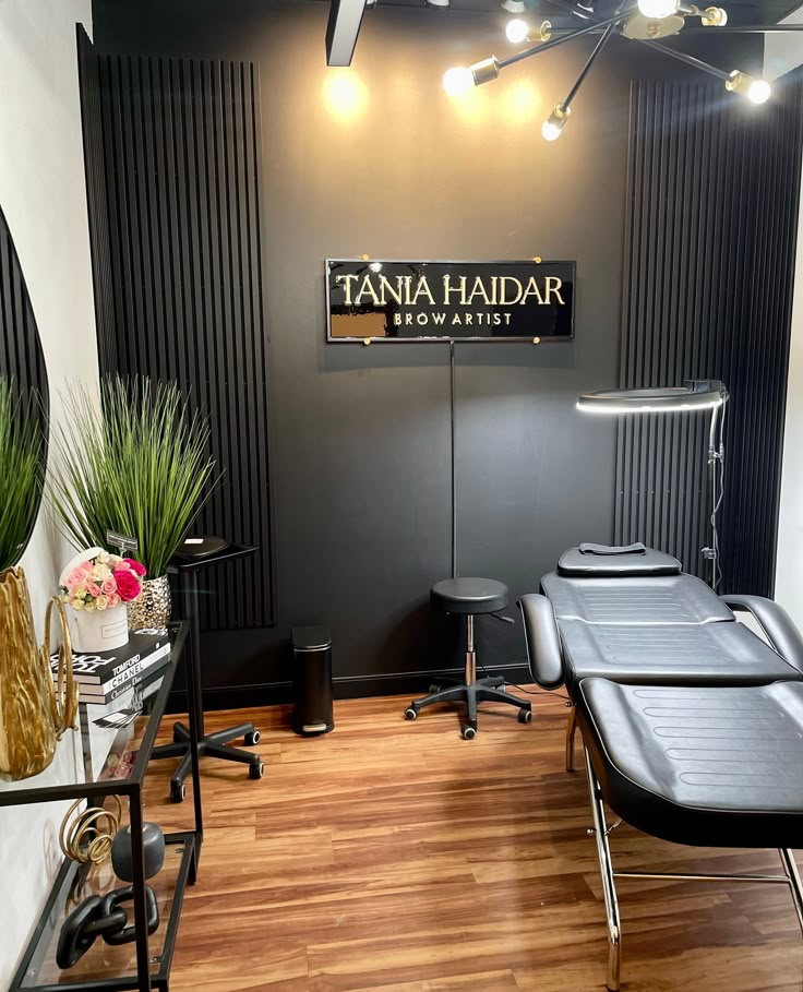 the interior of a hair salon with black chairs and wooden flooring, plants in vases