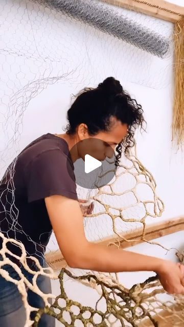 a woman is working on some kind of weaving project with yarn and wood in the background