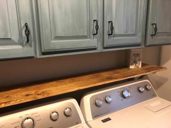 a washer and dryer in a room with wooden cabinets above the washer