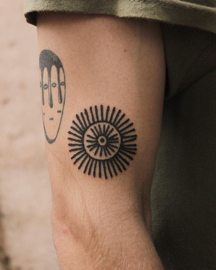 a man with a tattoo on his arm has an evil looking eye and the sun behind him