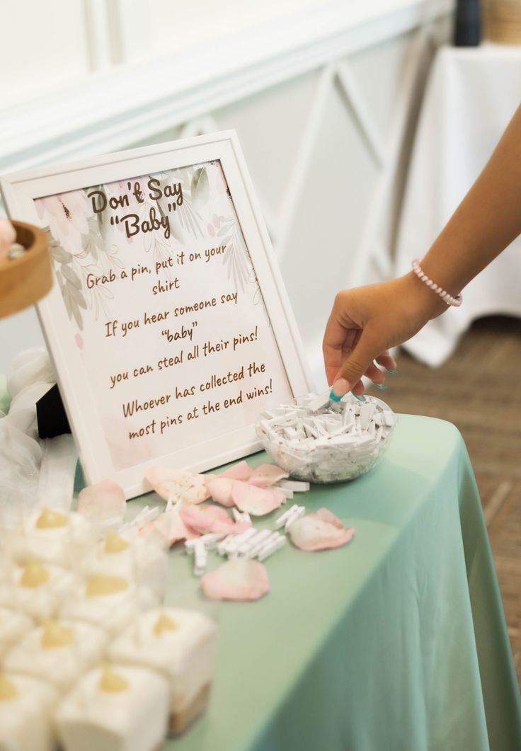 a table topped with lots of cupcakes next to a sign that says don't say baby