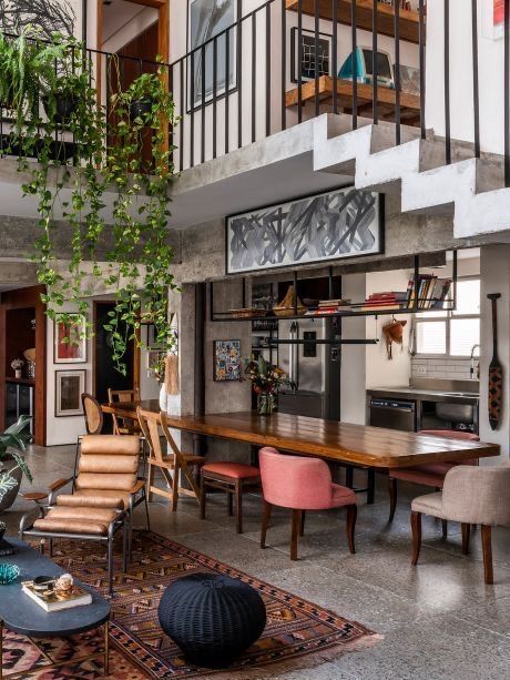 a living room filled with lots of furniture next to a tall plant hanging from the ceiling