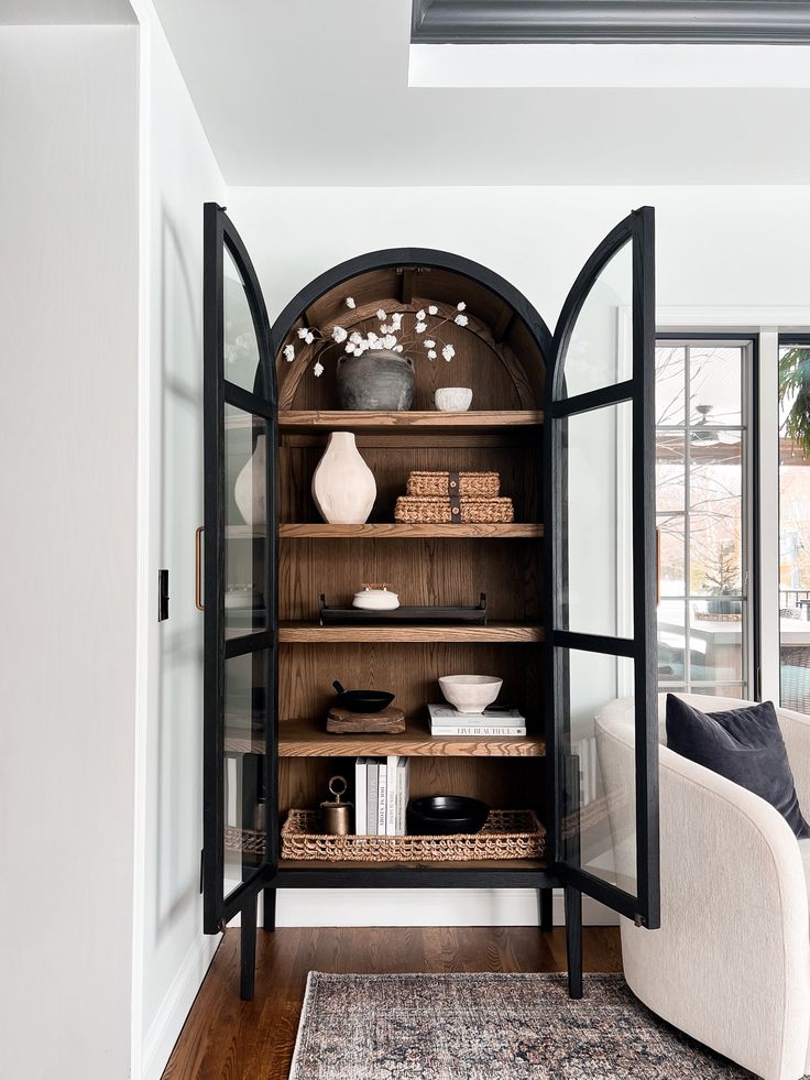 a living room filled with furniture and a book shelf next to a window on top of a hard wood floor