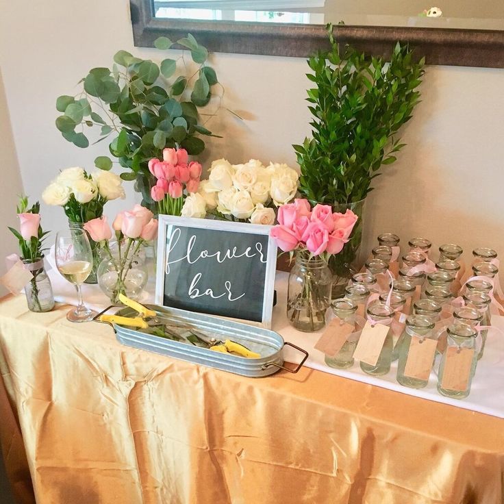 a table topped with lots of vases and flowers next to a chalkboard sign