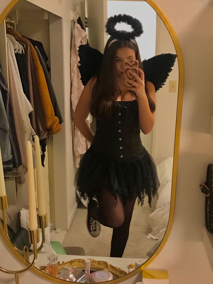 a woman taking a selfie in front of a mirror with an angel costume on