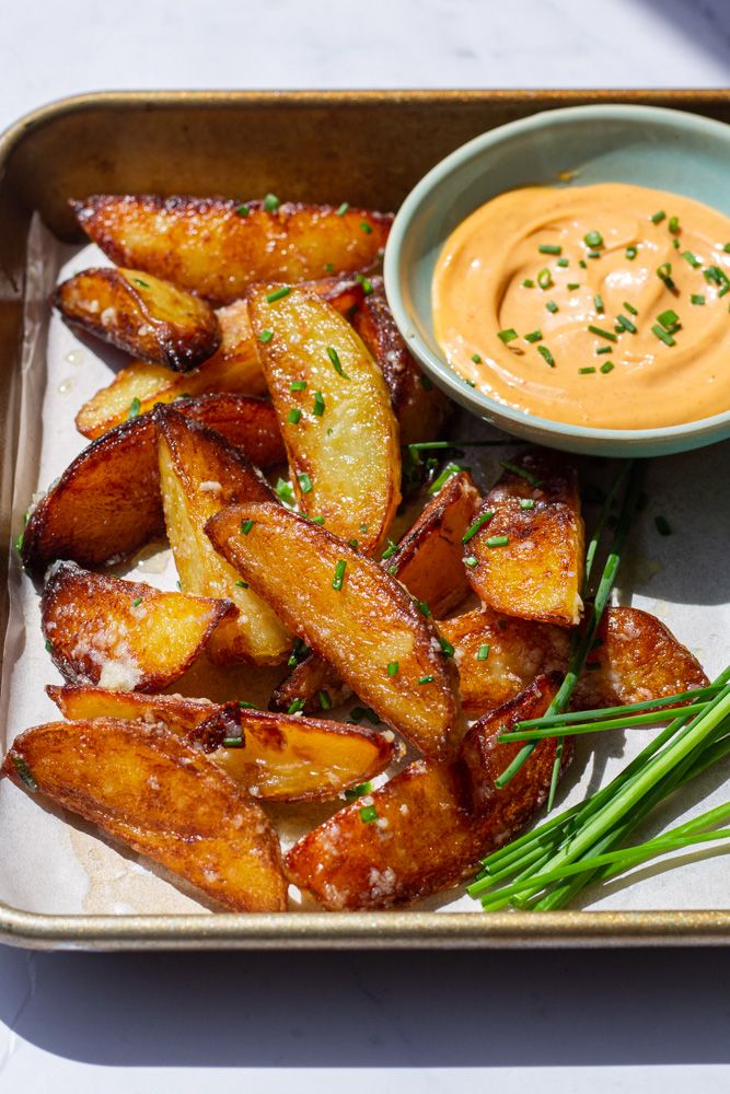 some fried potatoes with dipping sauce on the side