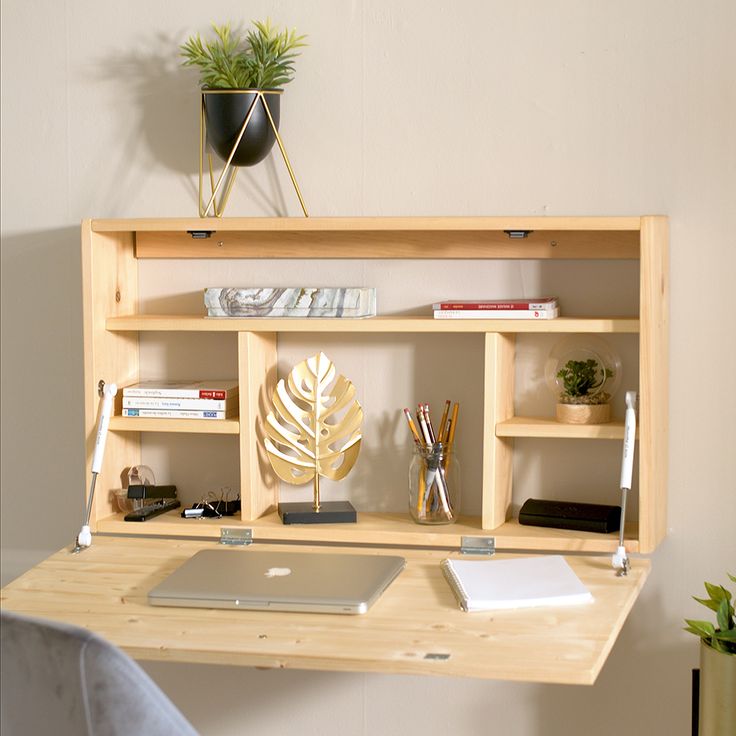 a wooden desk topped with a laptop computer next to a potted plant on top of it