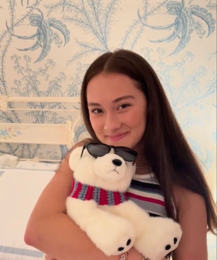 a young woman holding a white teddy bear in her arms and smiling at the camera