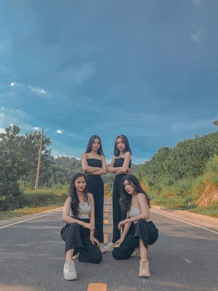 three women kneeling down in the middle of an empty road with their hands on each other's hips