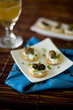 small appetizers on a plate next to a glass of orange juice