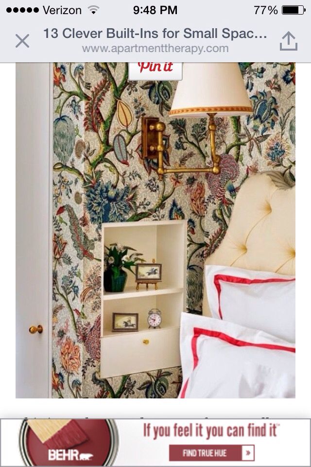 a bed room with a neatly made bed next to a wallpaper covered in flowers