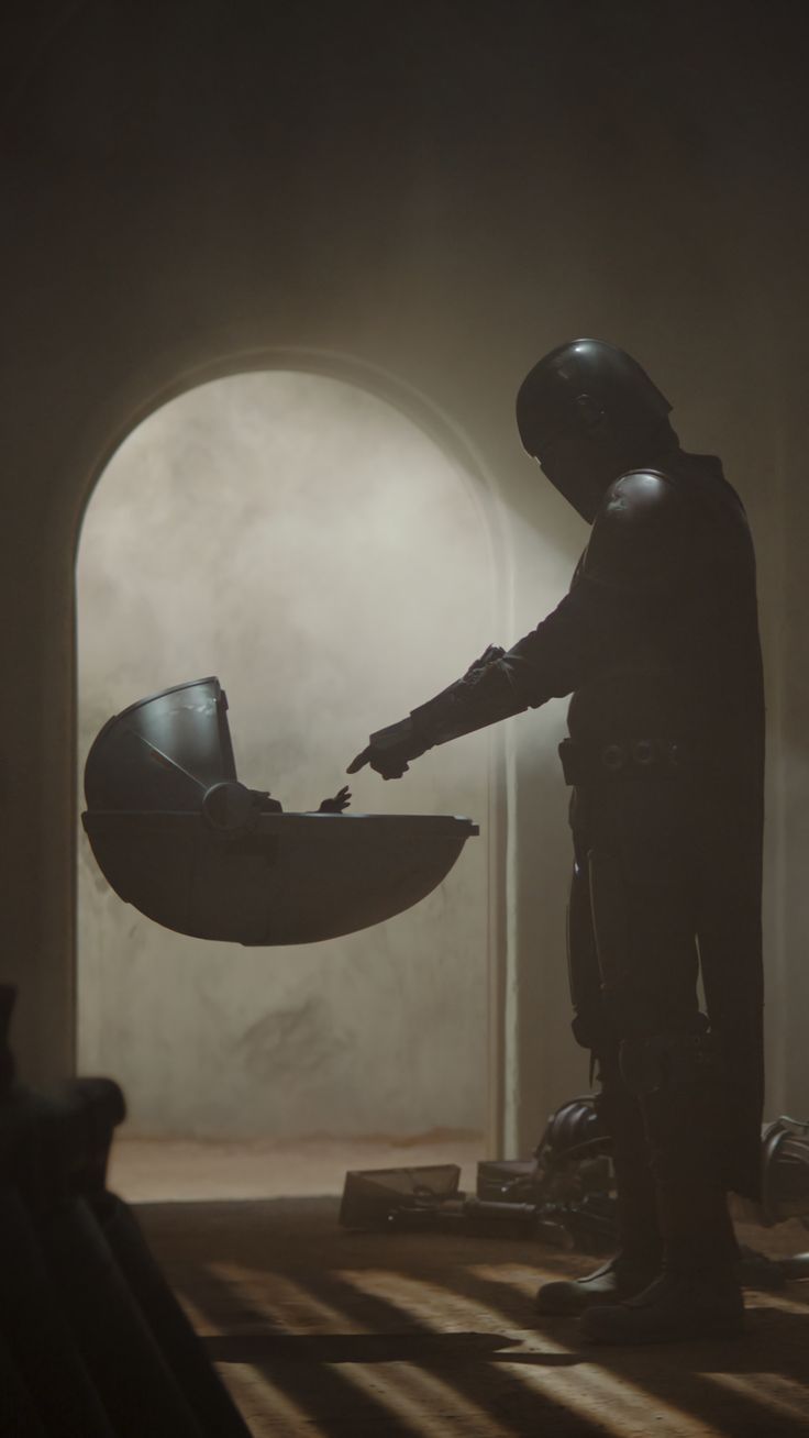 a person in a dark room with a helmet pointing at something on the floor next to him