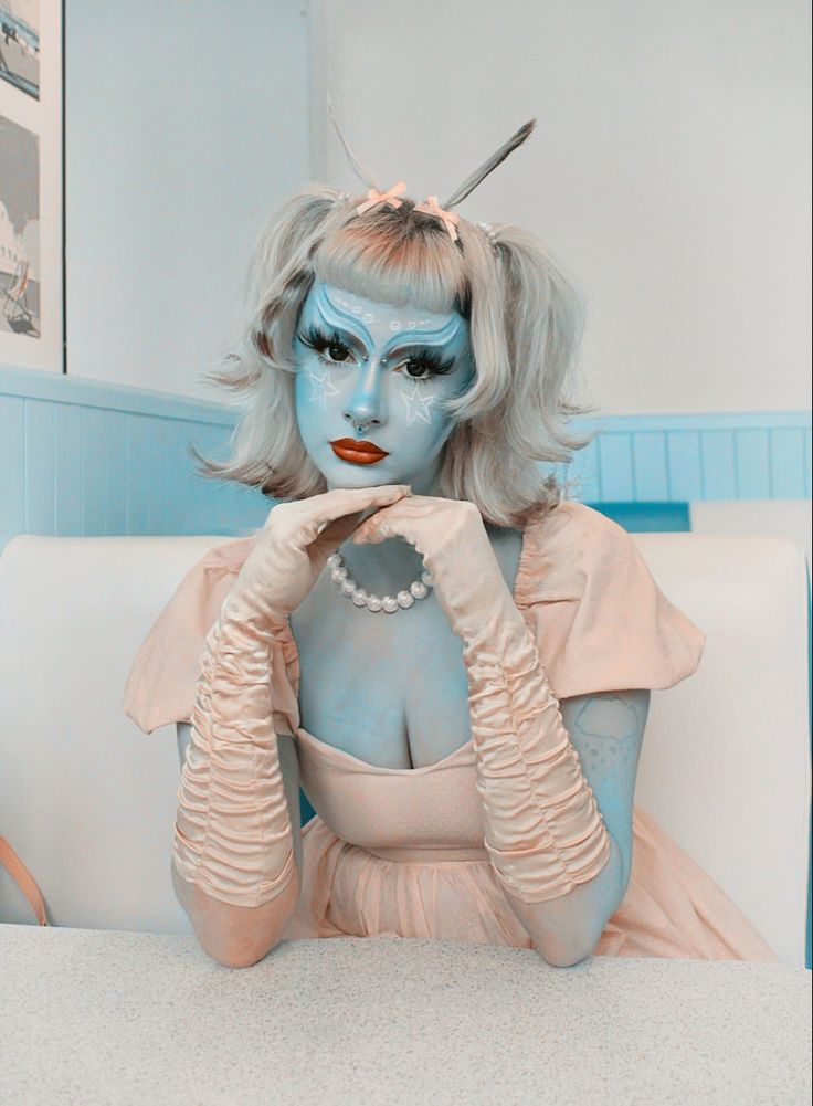 a woman with blue makeup sitting at a table