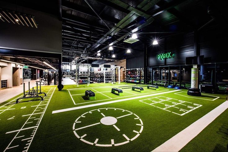 an indoor gym with artificial turf and various exercise equipment on the floor, along with neon lights