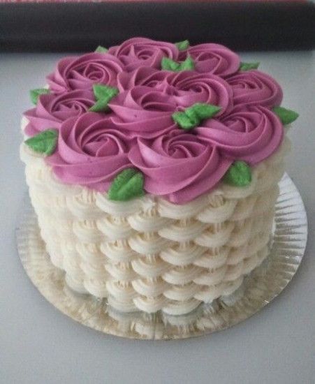 a white cake with pink frosting and green leaves